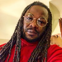 a man with dreadlocks and glasses taking a selfie